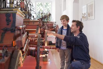 Erwachsener zeigt Kind ein Ausstellungsstück des Feuerwehrmuseums